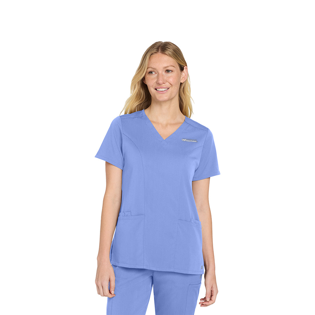 Woman wearing a blue scrub top with a visible brand logo on a white background